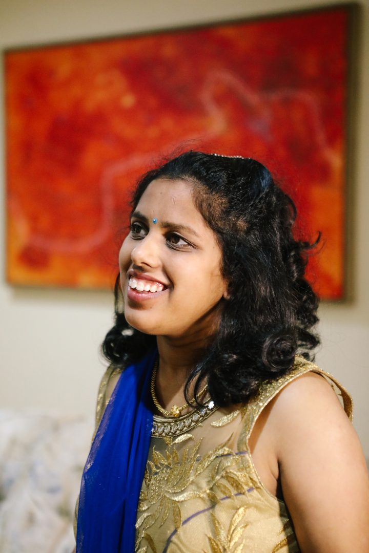 Picture of a 30yr old woman with black curly haird, wearing a gold top and blue scarf